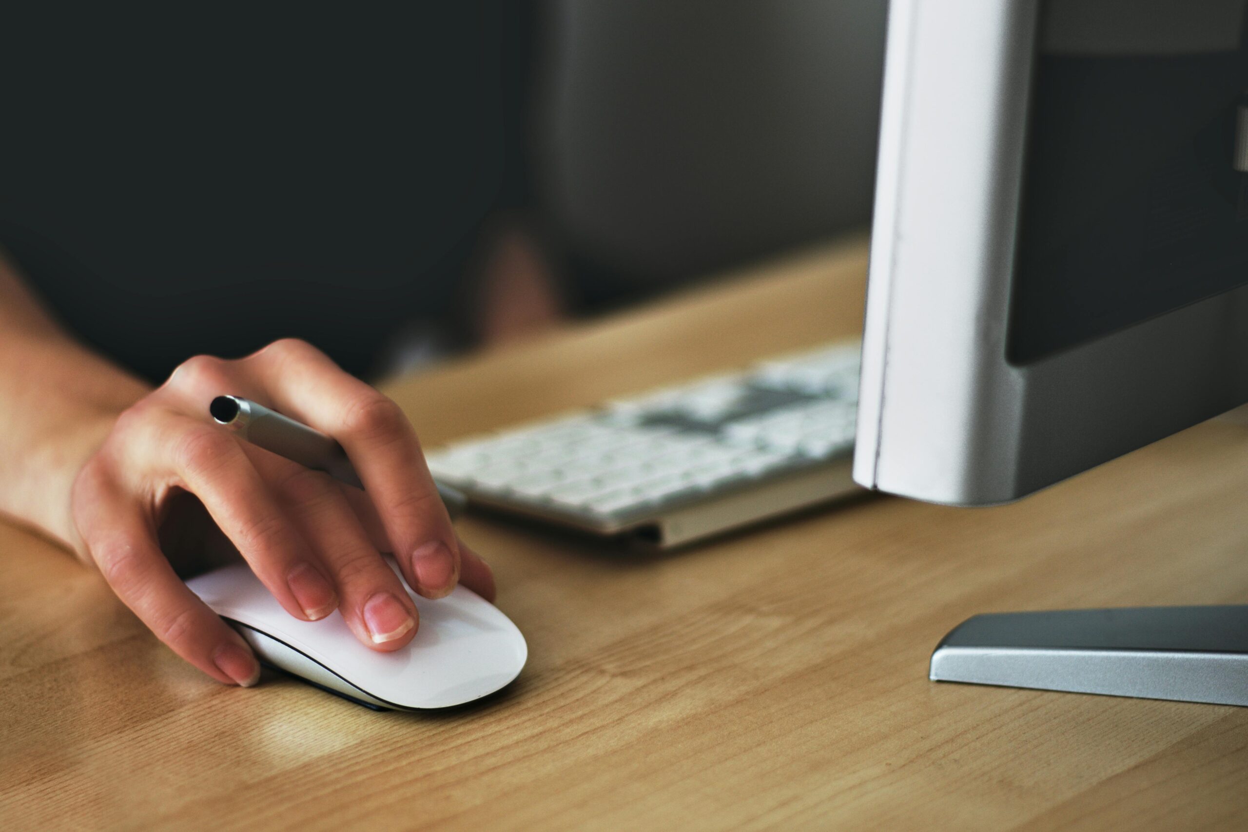 Opportunities A hand using a wireless mouse at a modern desk setup with a computer and keyboard.